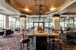 A spacious indoor dining area with a long table, multiple chairs, and a patterned carpet.