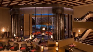 A modern lounge area with wicker furniture, a central seating arrangement, and a view of the outdoors. - 7 BR Golf Tennis SPA Lake Resort Villa (Paradise Valley)