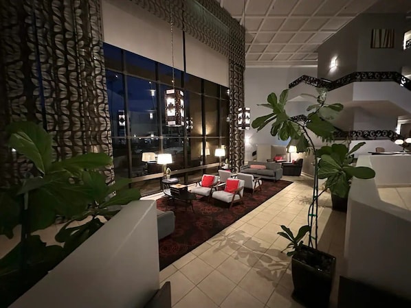 Un salon moderne doté d’une grande fenêtre, d’une cheminée et d’un coin salon agrémenté d’un tapis rouge.