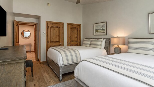 A bedroom with two beds, a ceiling fan, a desk, and a round mirror. - Riva Ridge Premium 745 | 2BR Vail Village (Vail)