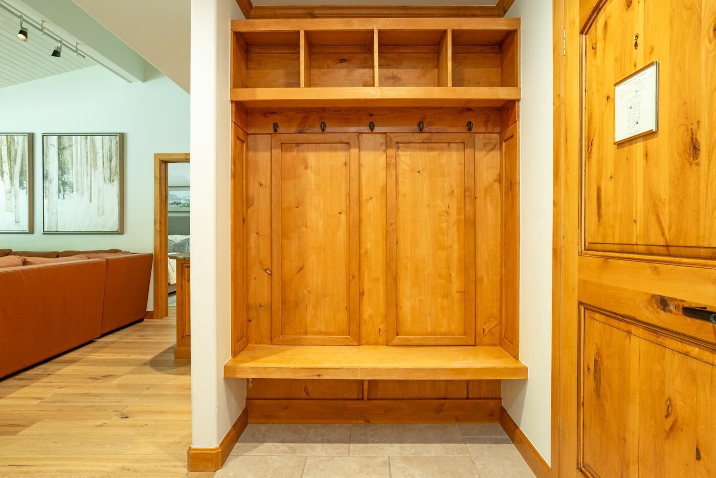 A wooden wardrobe with multiple compartments and a built-in bench.
