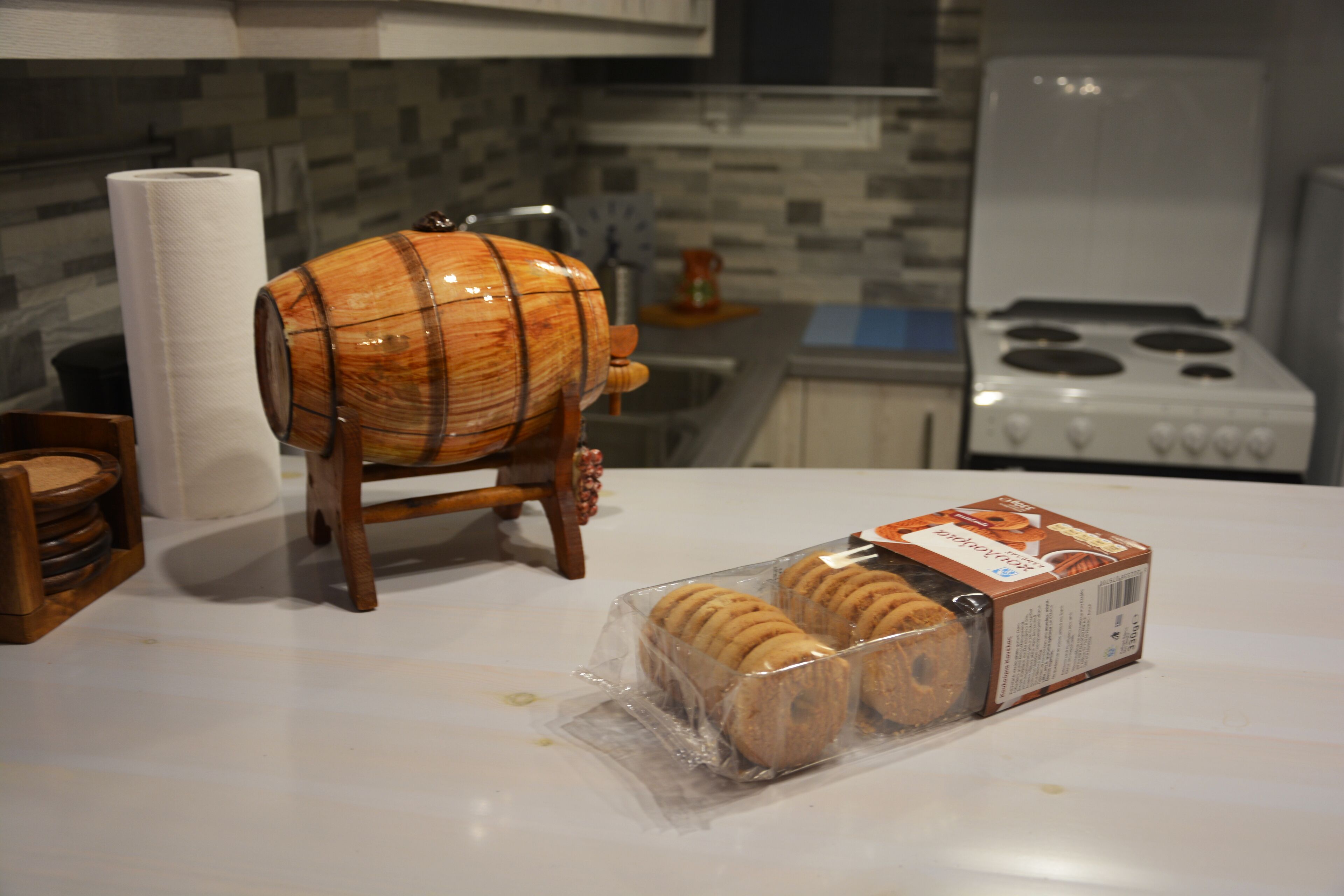 A kitchen with a wooden barrel, a roll of paper towels, and a package of cookies on the counter.