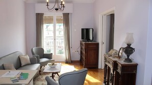 A living room with a sofa, armchair, coffee table, and a television on a wooden cabinet. - Vintage,spacious apartment in the heart of Athens! (Athina)