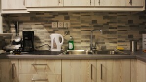 A kitchen with wooden cabinets, a coffee maker, a kettle, a dish soap bottle, and a sink. - Vintage,spacious apartment in the heart of Athens! (Athina)