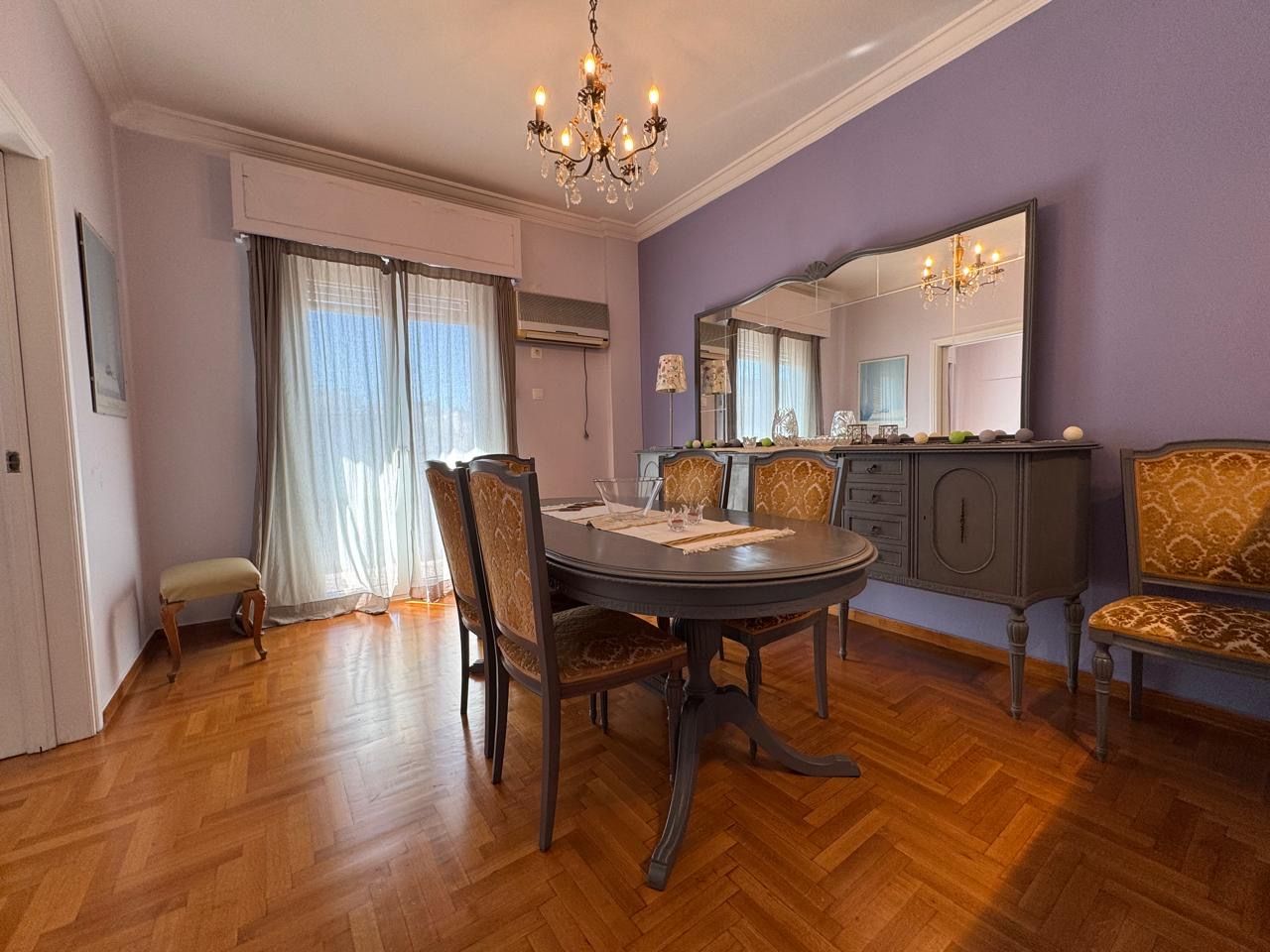 A dining area with a round table, chairs, a bench, and a cabinet.