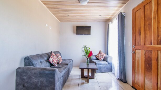 Un salon moderne avec deux canapés gris, une table basse en bois et un téléviseur fixé au mur.