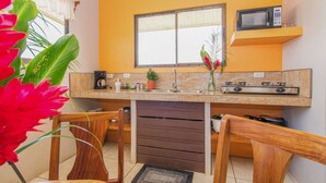 Une cuisine avec une fenêtre, un four à micro-ondes, un évier et des chaises en bois.