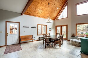 A dining area with a wooden table and chairs, a bench, and a chandelier.