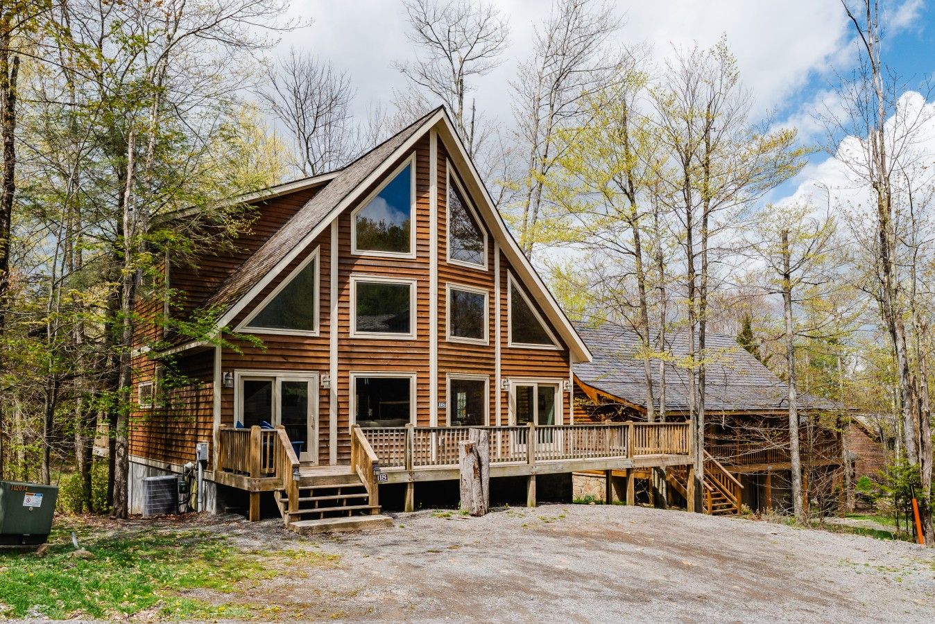 A cabin with a wooden exterior, a porch, and a staircase leading to a deck.