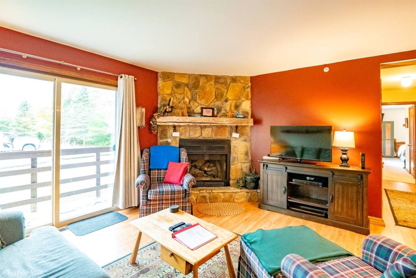Een woonkamer met een stenen openhaard, een televisie en een bank.