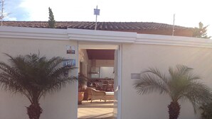A building with a tiled roof, a sign indicating a property number, and a door leading to an interior space. - SINGLE STOREY HOUSE - COMFORT AND LEISURE - ENSEADA - GUARUJÁ - (Guarujá)