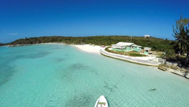 A coastal resort with a clear turquoise sea, a white sandy beach, and a small building with a green roof. - Secluded beach house on Hooper's Bay, Great Exuma, The Bahamas (George Town)