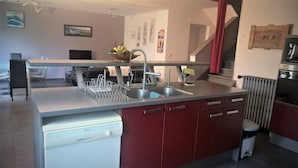 A modern kitchen with a built-in dishwasher, a stainless steel sink, and red cabinetry. - Beaucaire Avignon, Camargue  (Beaucaire)