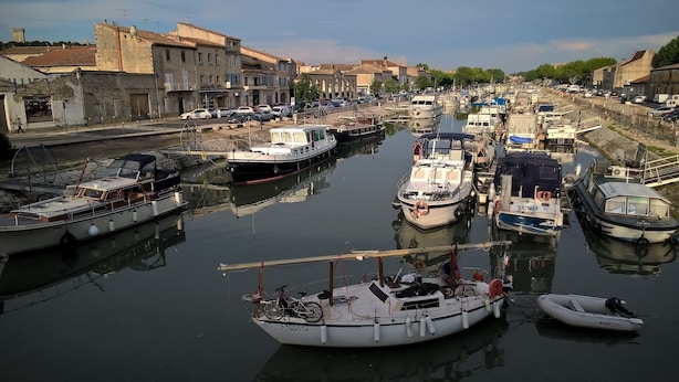 A marina with various boats docked, surrounded by buildings and a calm waterway. - Beaucaire Avignon, Camargue  (Beaucaire)