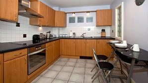 Eine Küche mit Holzausbau, einer schwarzen Arbeitsplatte, einem Spülbecken und einem Essbereich mit Tisch und Stühlen.