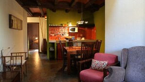 Un soggiorno accogliente con zona pranzo, cucina con piastrelle rosse e parete verde decorativa.