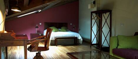 A room with a bed, wooden furniture, a glass table, and a green sofa.