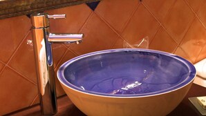 Un bagno con un lavandino blu capiente, un rubinetto cromato e uno specchio sopra.