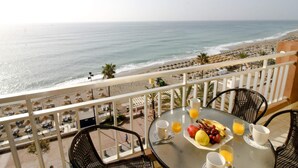 A balcony with a table set for breakfast overlooking a beach. - SUITUR APARTMENT YATE BEACHFRONT FUENGIROLA (Fuengirola)