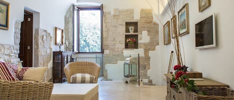 A cozy living room with a stone wall, wicker furniture, and framed pictures on the wall.