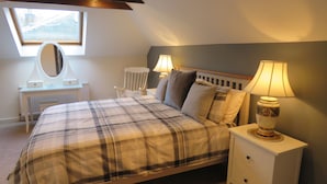 A bedroom with a bed, bedside tables, a lamp, a mirror, and a window.