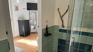 Uma cozinha compacta com geladeira, micro-ondas e estante.