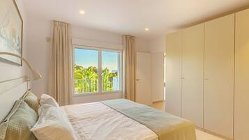Un dormitorio con una cama grande, un armario y una ventana con vistas a zonas verdes.