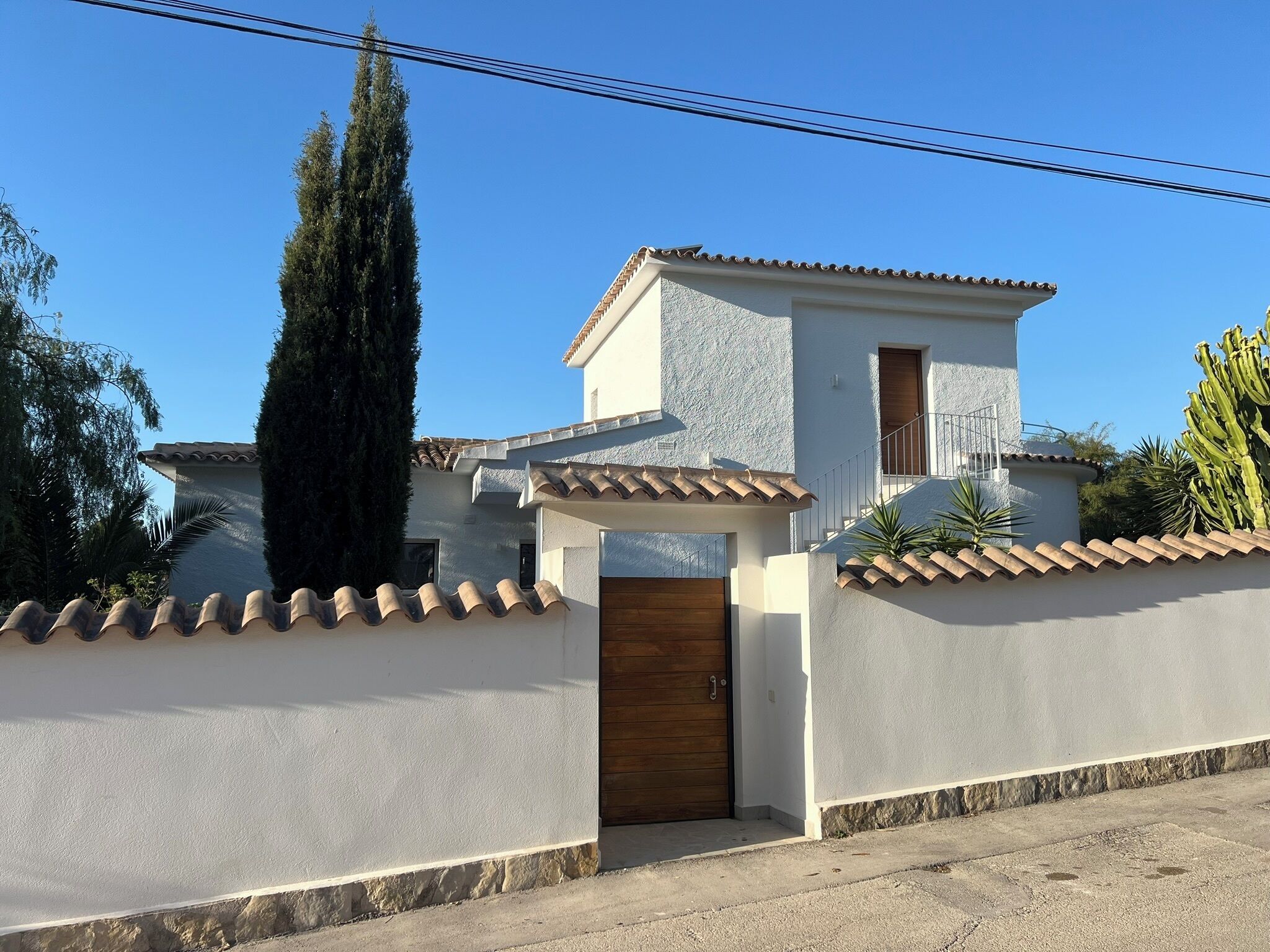 Una casa de dos pisos con fachada blanca, una puerta de madera y un balcón pequeño.