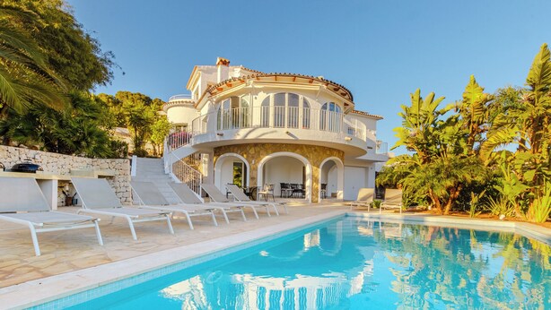 Un'ampia e lussuosa casa con piscina, area relax esterna e vegetazione tropicale.