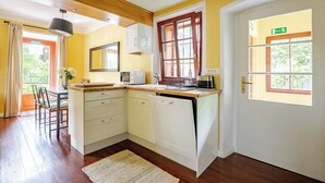 Cozinha compacta com armários brancos, bancada de madeira e máquina de lavar louça embutida.