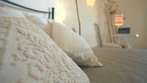 A bed with a knitted blanket and pillows, a bedside table with a lamp, and a wall-mounted light fixture. - VILLA DEL MARE IN CHIA, WITH POOL OVERLOOKING THE SEA AND TOWER (Domus de Maria loc. Chia)