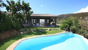 A swimming pool with a covered patio area, a stone wall, and a view of a hillside. - VILLA DEL MARE IN CHIA, WITH POOL OVERLOOKING THE SEA AND TOWER (Domus de Maria loc. Chia)