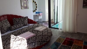 A modern bedroom with a red sofa bed, a patterned bedspread, a colorful rug, a painting, and a large mirror. - Romantic luxury "honeymoon" hideaway in the hills above Kalkan in a rural idyll (Kas)