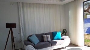 A modern living room with a grey sofa, blue cushions, a floor lamp, and a patterned rug. - Romantic luxury "honeymoon" hideaway in the hills above Kalkan in a rural idyll (Kas)