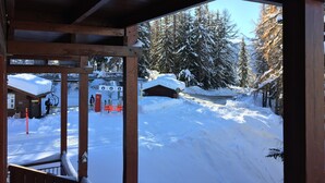 A wooden cabin with a view of a snowy landscape and a ski lift in the background.
