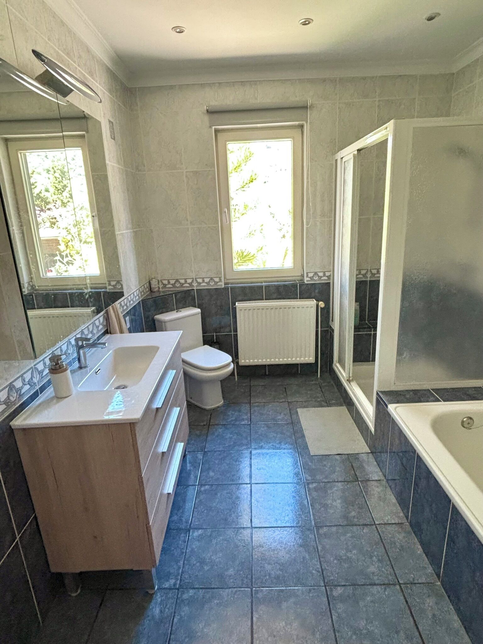Een badkamer met een bad, toilet, wastafel en een raam.