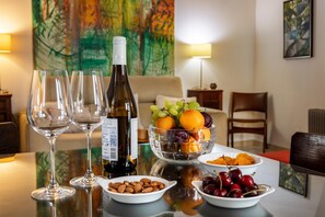 A dining table with wine bottles, glasses, and a fruit bowl.