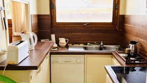 A compact kitchen with a dishwasher, a toaster, a kettle, and a sink.