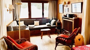 A cozy living room with a sofa, chairs, a small table, and a television.