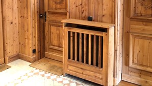 A wooden room with a door, a small wooden bench, and a tiled floor.