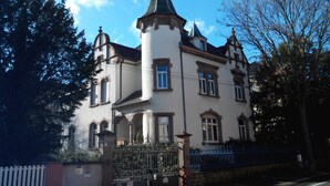 Un edificio storico con una torre imponente, finestre simmetriche e un ingresso chiuso da un cancello.