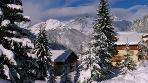 Een berglandschap bedekt met sneeuw, met een chalet met houten gevel en een balkon.