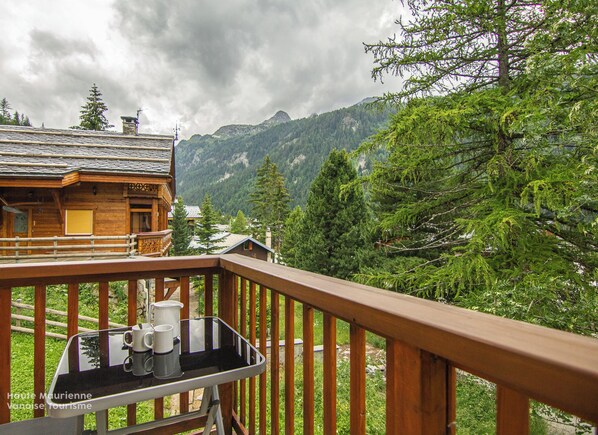 A wooden cabin with a balcony overlooking a mountainous landscape.