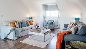 A modern loft apartment with a loft bed, a dining area, and a seating area with sofas and a coffee table. - Heart of St Ives, Parking, Superb Views, Sleeps 6 (Saint Ives)