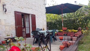 A patio area with a table and chairs, a wooden deck, and potted plants.