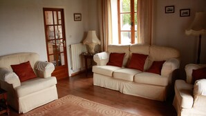 A living room with a beige sofa set, a wooden floor, a patterned rug, and a door with a glass panel.