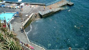 Una playa con piscina, muelle y gente disfrutando del agua.