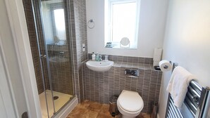 Ein Badezimmer mit einer Duschkabine, einem weißen Waschbecken und einer Toilette.