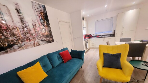 Ein modernes Wohnzimmer mit einem türkisfarbenen Sofa, einem gelben Sessel und einer Stadtbild-Mural an der Wand.