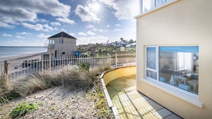 A coastal property with a beach view, a fenced garden, and a building with a balcony. - Seaview Apartment, Silversands, Rosslare Strand, Co. Wexford (Rosslare STrand)